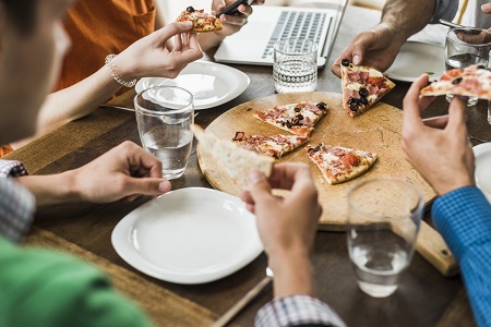 Gros plan de collegues qui partagent une pizza pendant une reunion.